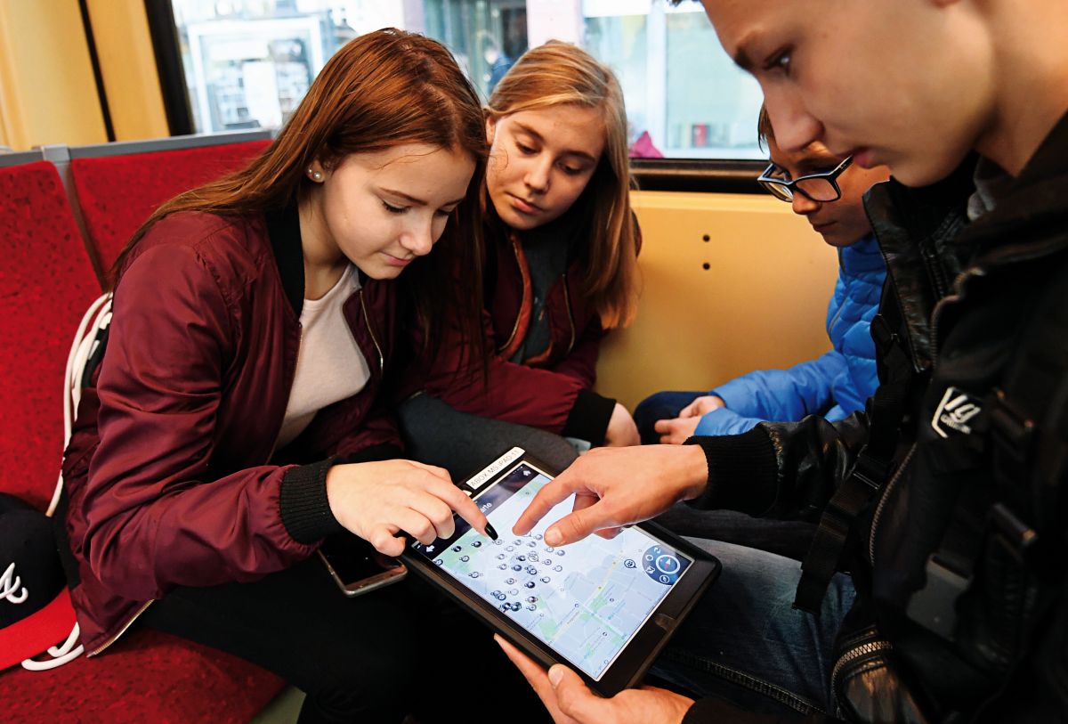 Eine Gruppe aus Schülern und Schülerinnen spielt während eines Wandertages eine Tablet-basierte Stadtrallye in Münster