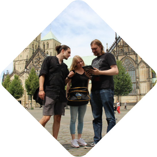 Eine Gruppe spielt auf dem Domplatz in Münster eine Stadtrallye der Adventurebox Münster als Betriebsausflug